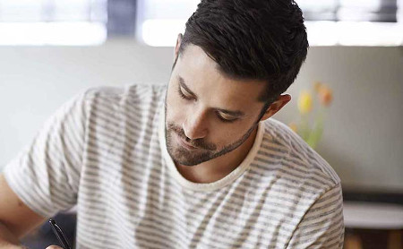 Man suffering from Tinnitus while writing in a coffee shop in Torrance CA