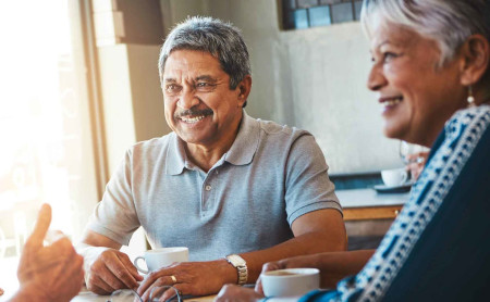 A group of mature, diverse friends enjoy a chat over coffee without hearing issues